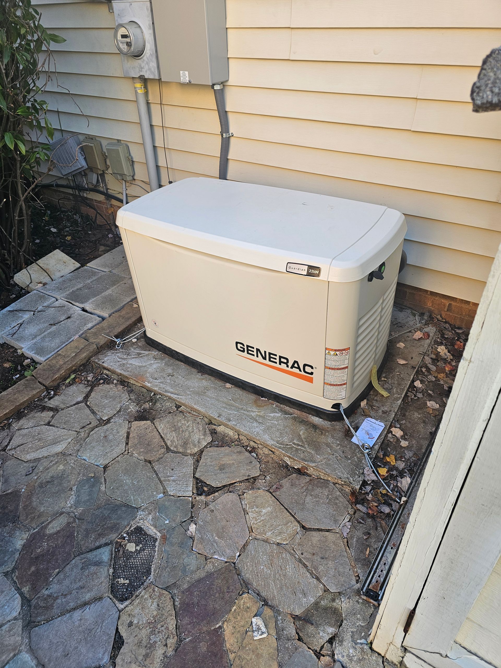 A generator is sitting on the side of a house