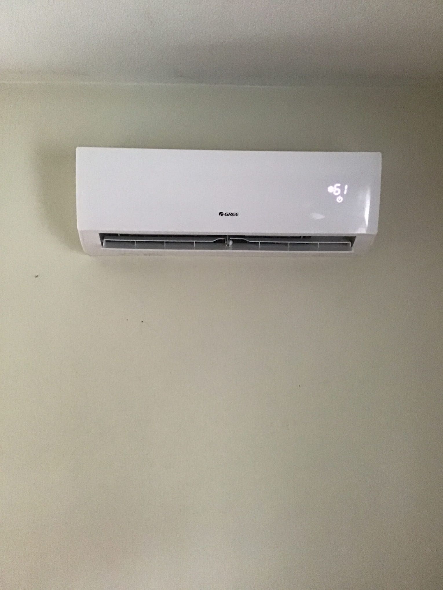 A white air conditioner is hanging on a wall in a room