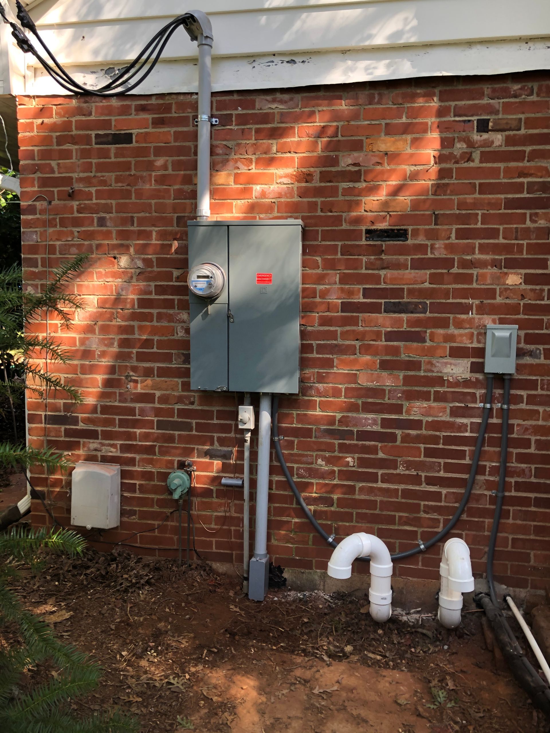 A brick wall with a box and pipes attached to it