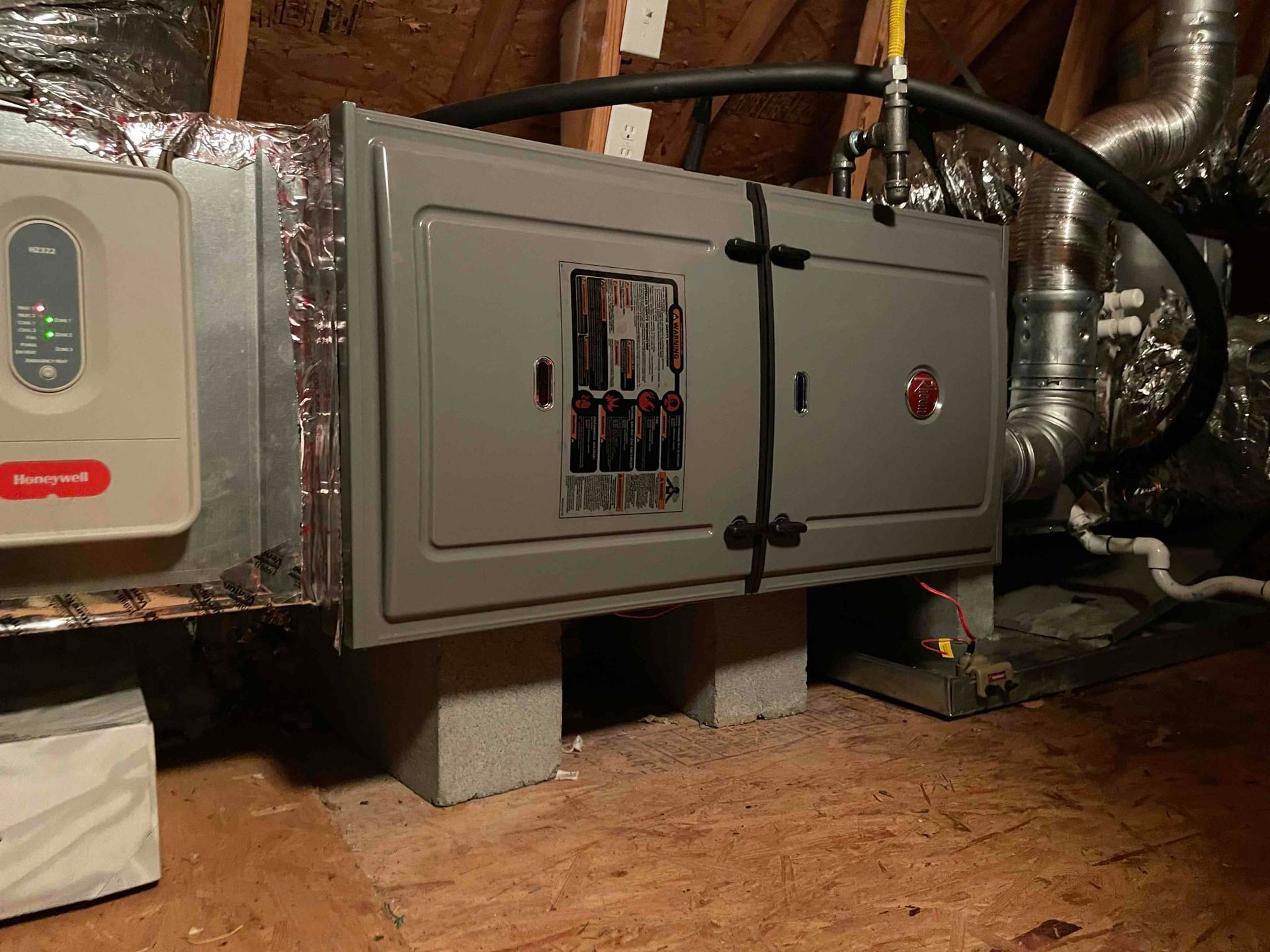 A electrical box is sitting in the attic of a house