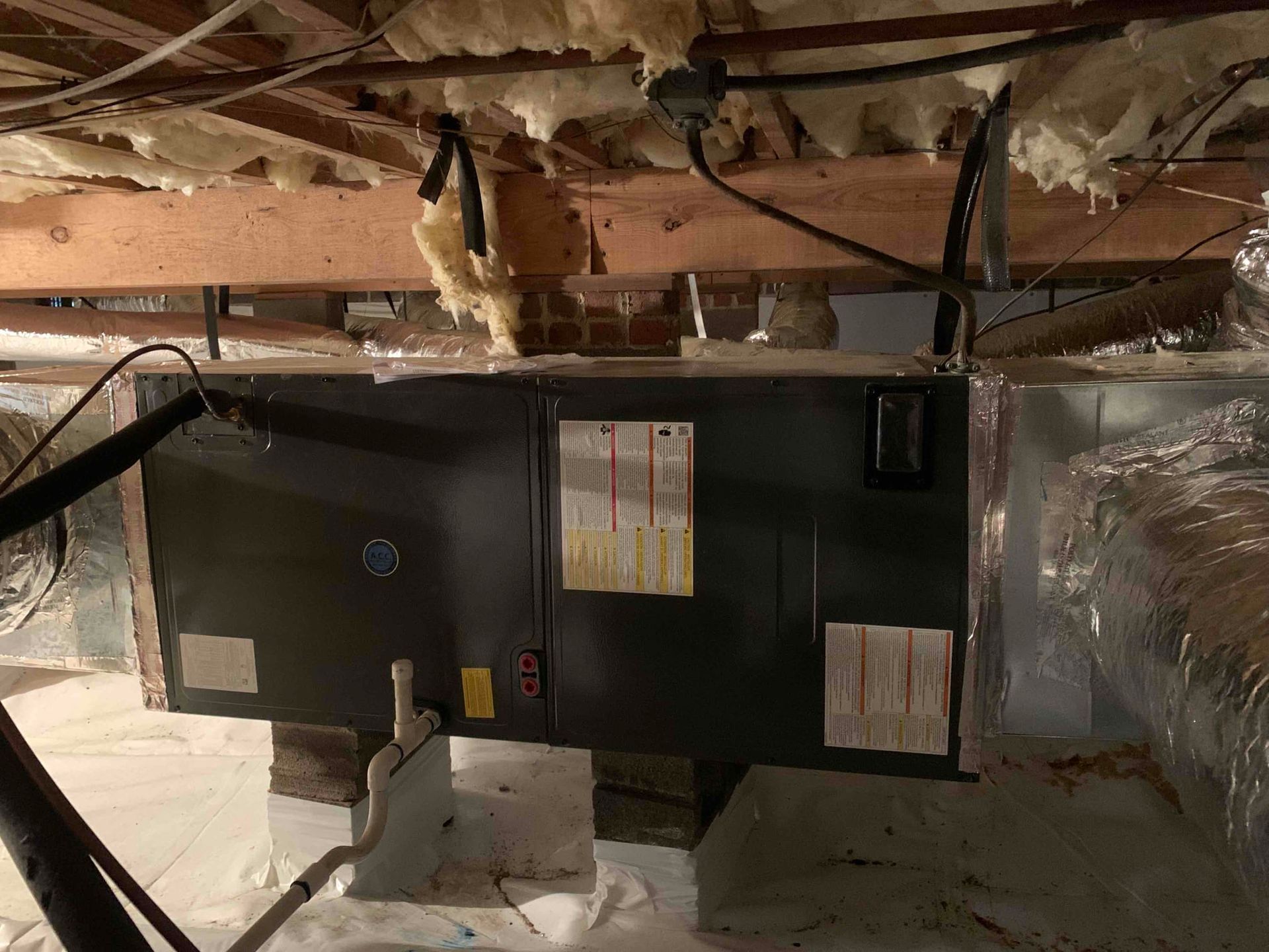 An air conditioner is hanging from the ceiling of a basement