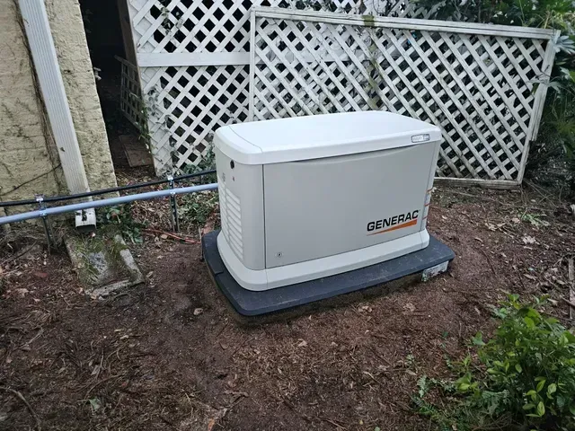 A generator is sitting in the dirt in front of a house