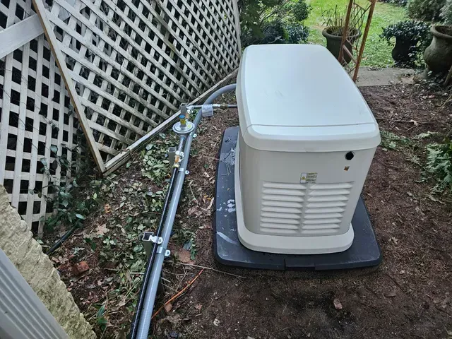 A white generator is sitting on top of a black tray in the dirt