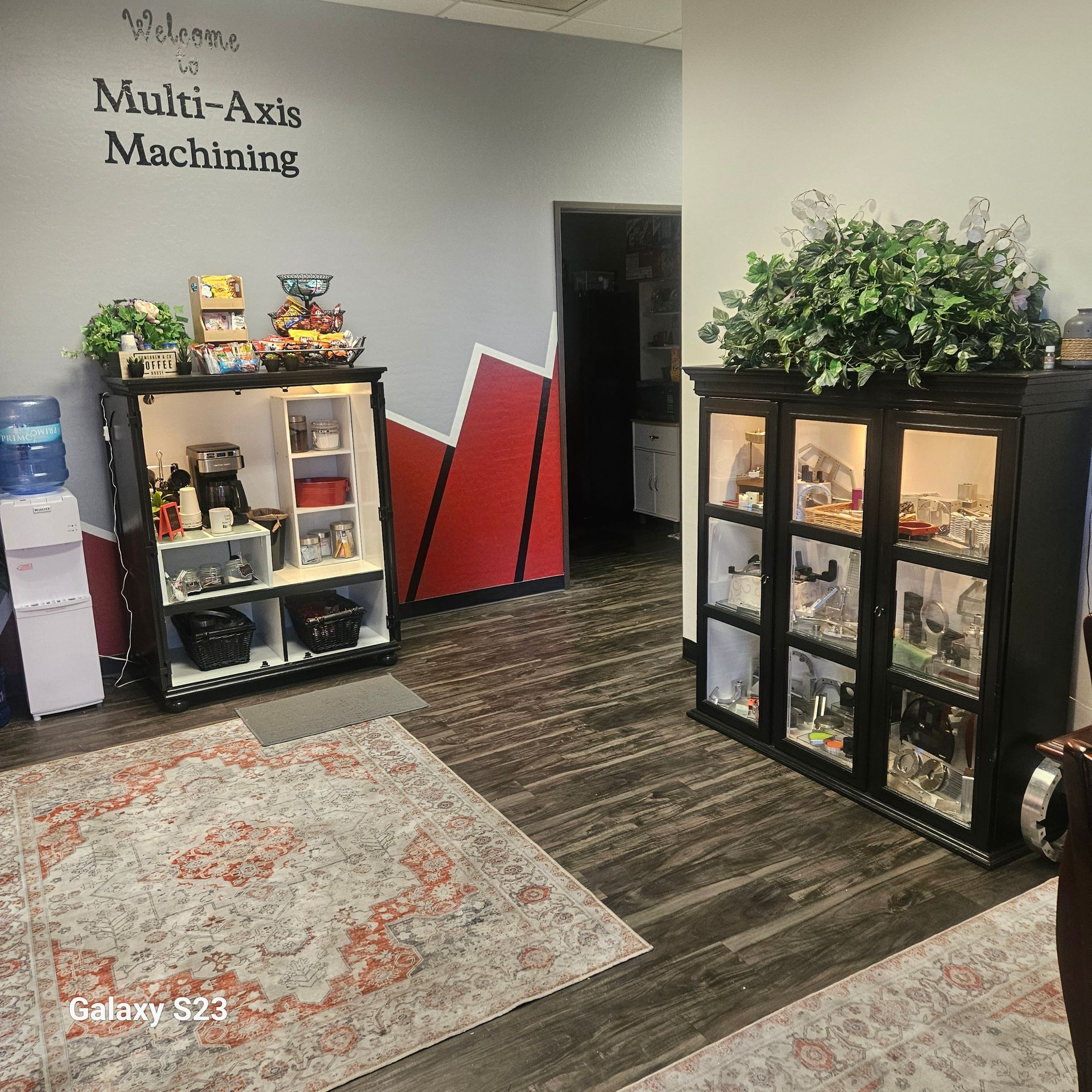 A waiting area with wood floors, two display cabinets, a water cooler, and 