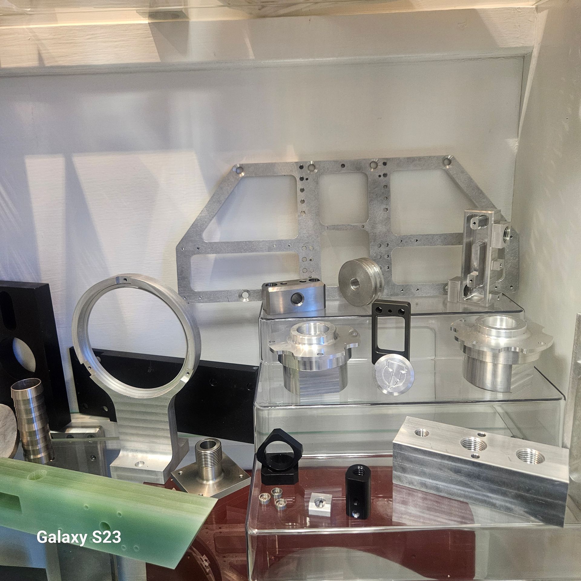 A display shelf showcasing various precision-machined metal and plastic components and industrial parts.