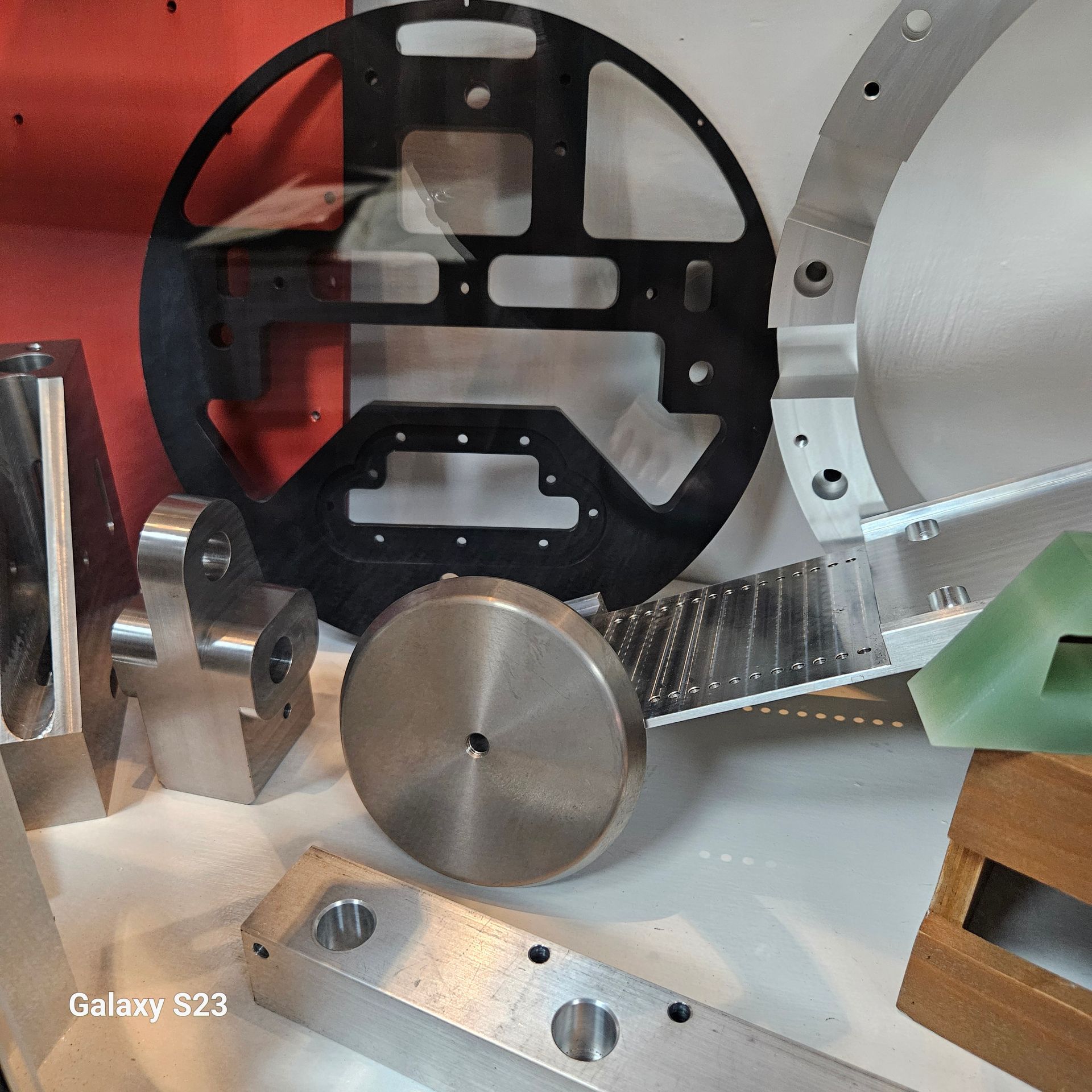 A collection of assorted metallic and black precision-machined industrial parts resting on a white surface.