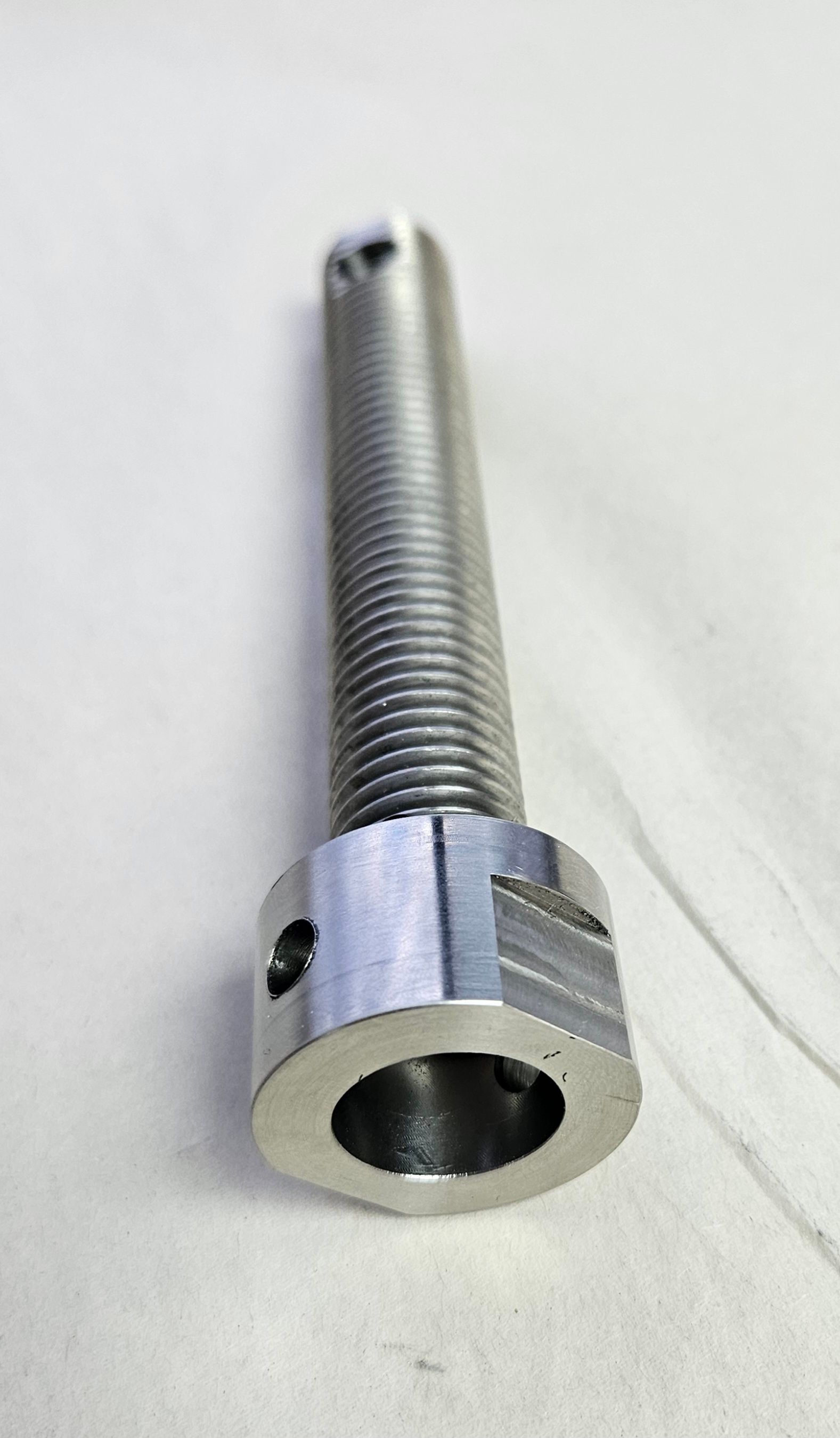 A metallic cylindrical bolt with a threaded shaft, a hexagonal head, and small side holes, isolated on a white background.