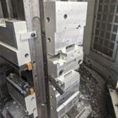 Metal industrial machine components arranged in a vertical stack within a manufacturing environment.