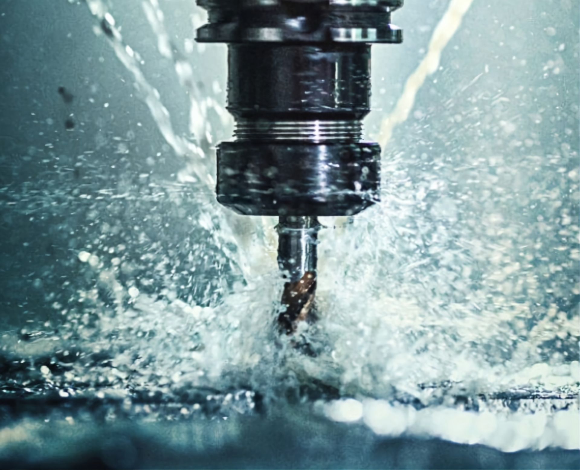 A metal cutting tool operates on a workpiece while bathed in a cooling fluid spray.