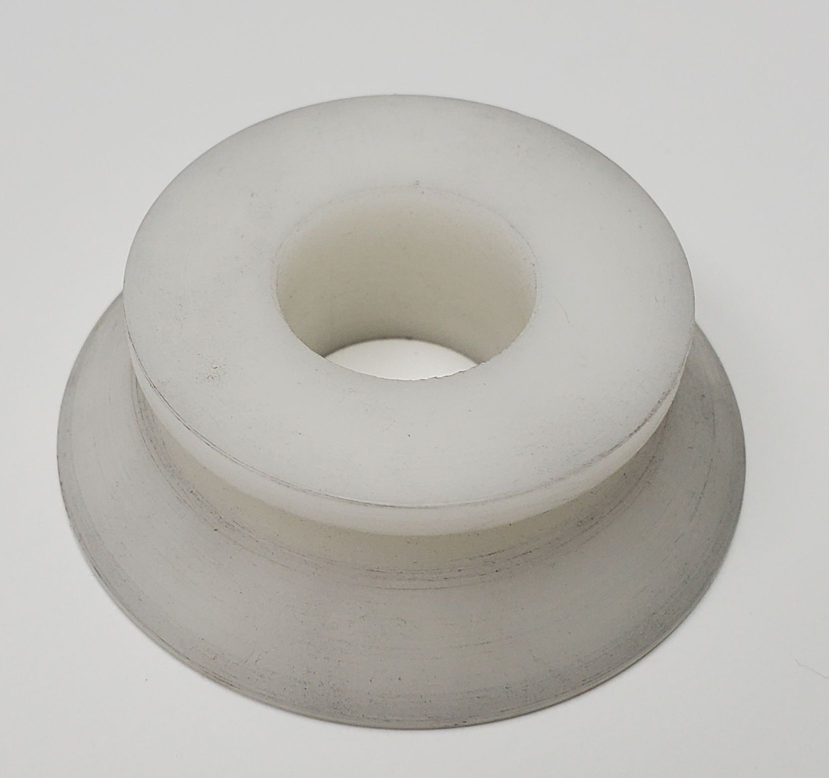 A white, circular plastic roller or guide with a recessed center, set against a plain light gray background.
