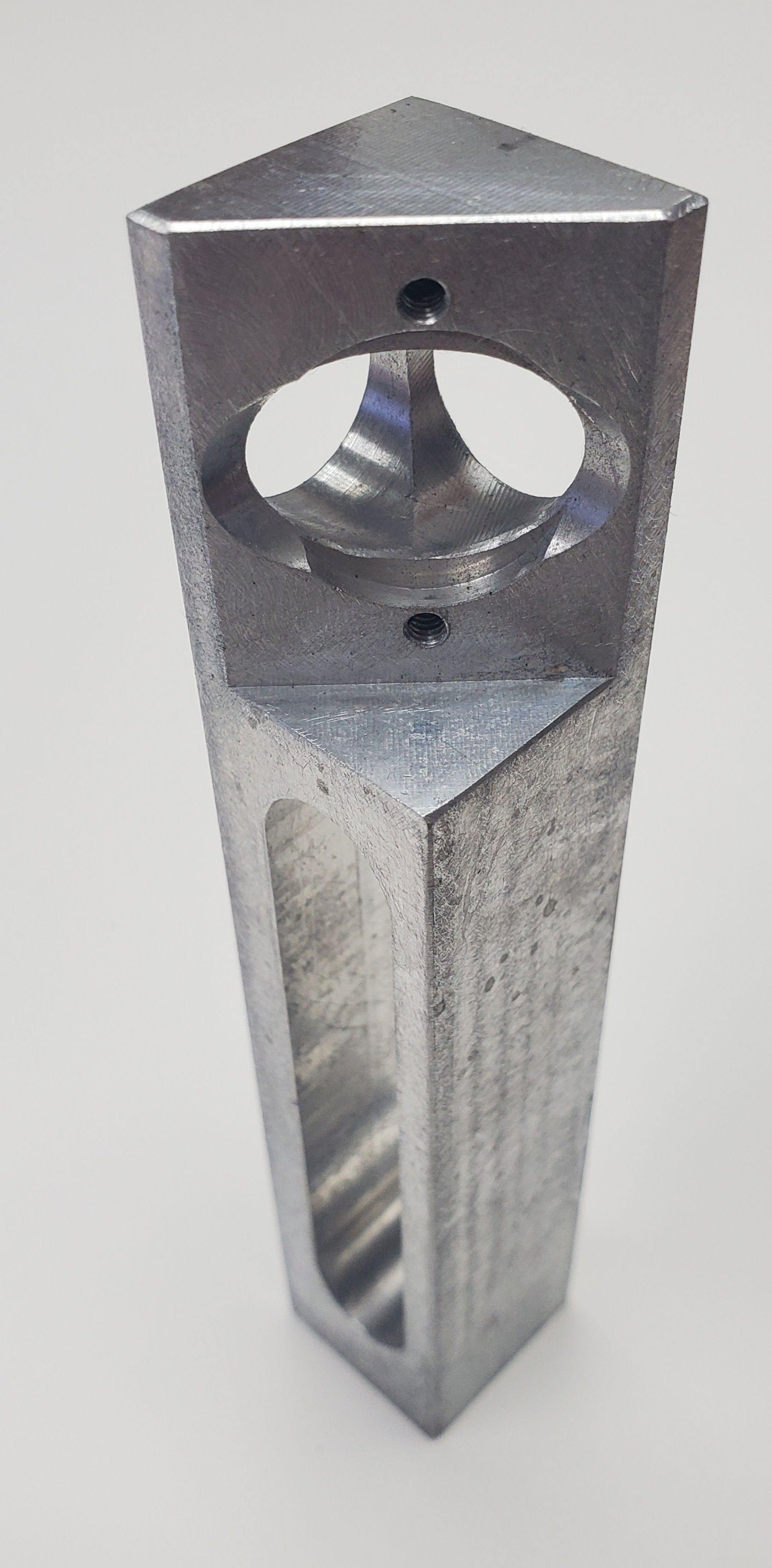 A machined aluminum triangular post with a circular cutout at the top and a vertical rectangular slot along the side.