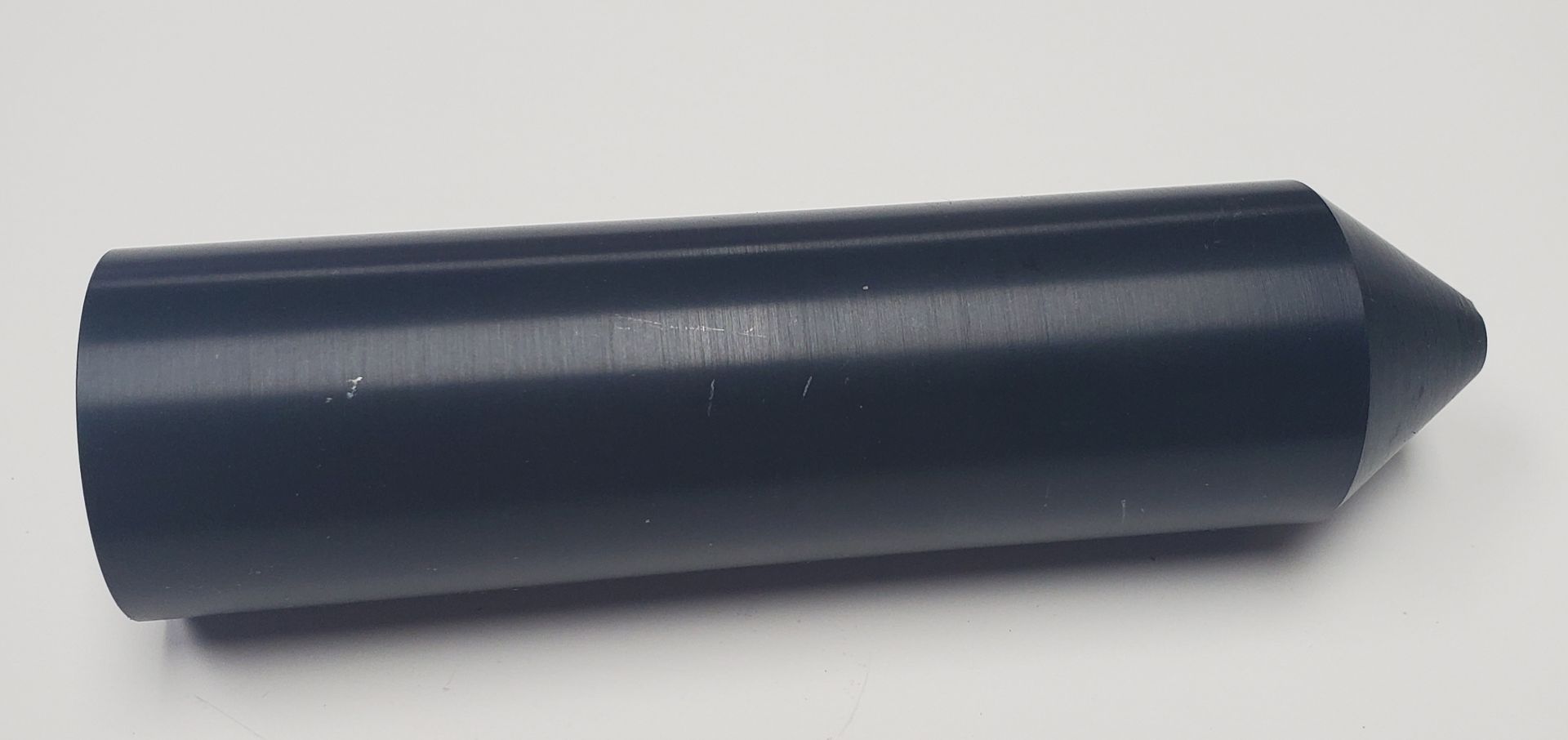 A matte black, cylindrical tool with a tapered, cone-shaped tip, resting horizontally against a plain white background.