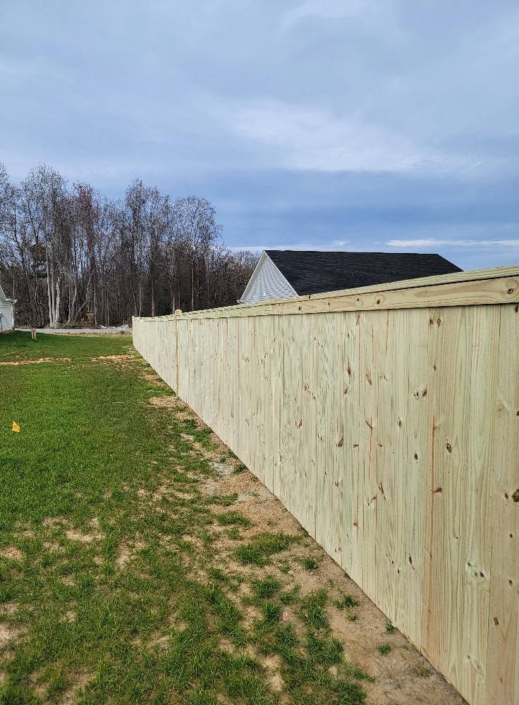 Wooden privacy fence stretching across a grassy yard under a cloudy sky