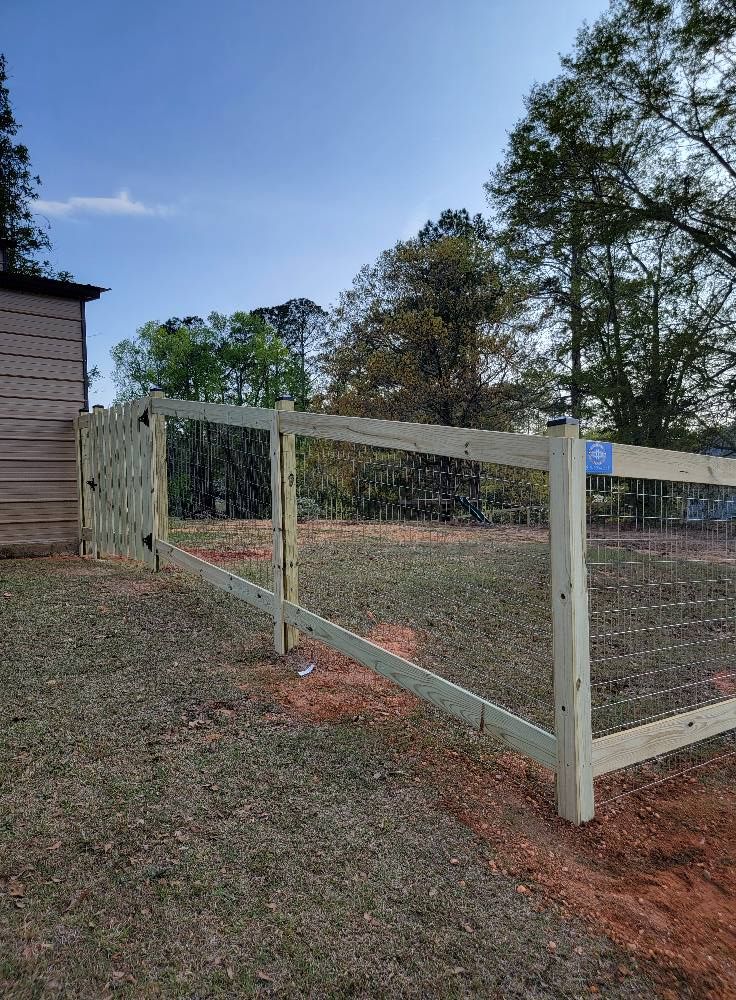 Wooden fence under construction beside a house in a grassy yard