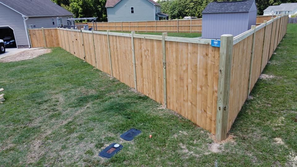 Wooden privacy fence enclosing a yard, with a gate and neighboring houses in the background.