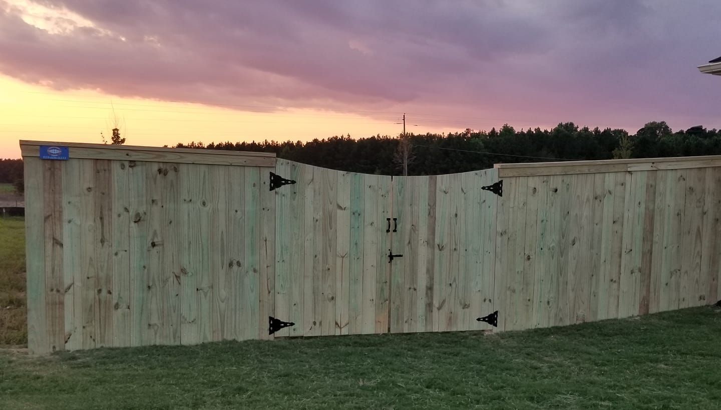Large wooden fence at sunset with purple sky and trees in the background