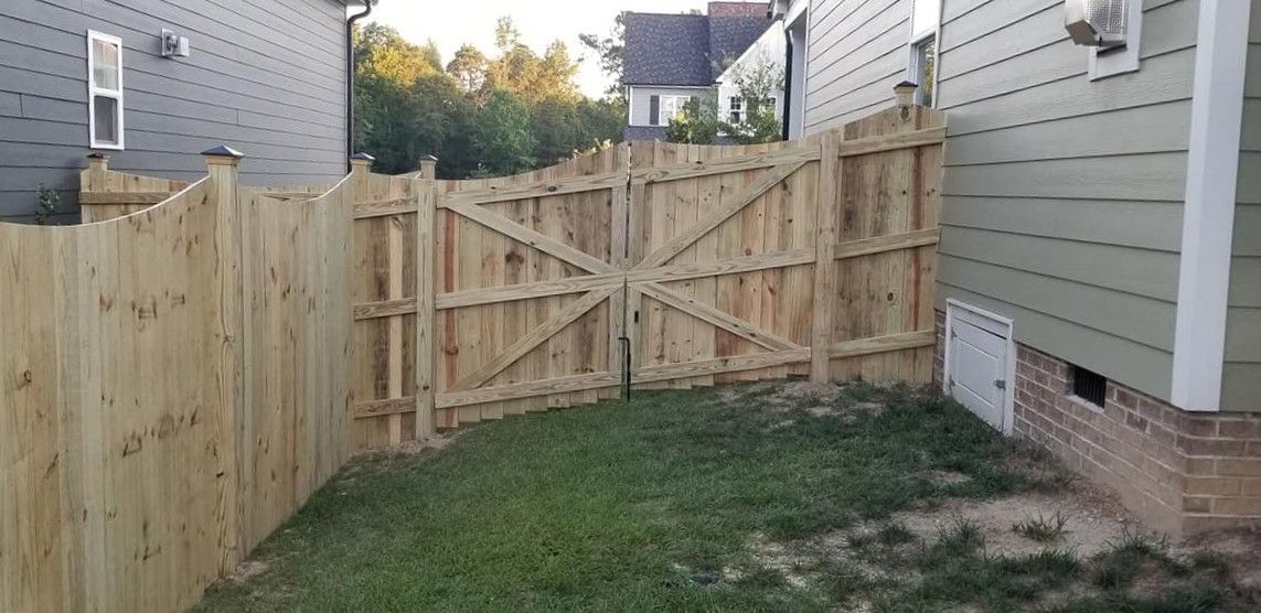 Wooden gate between two houses at the end of a narrow grassy side yard