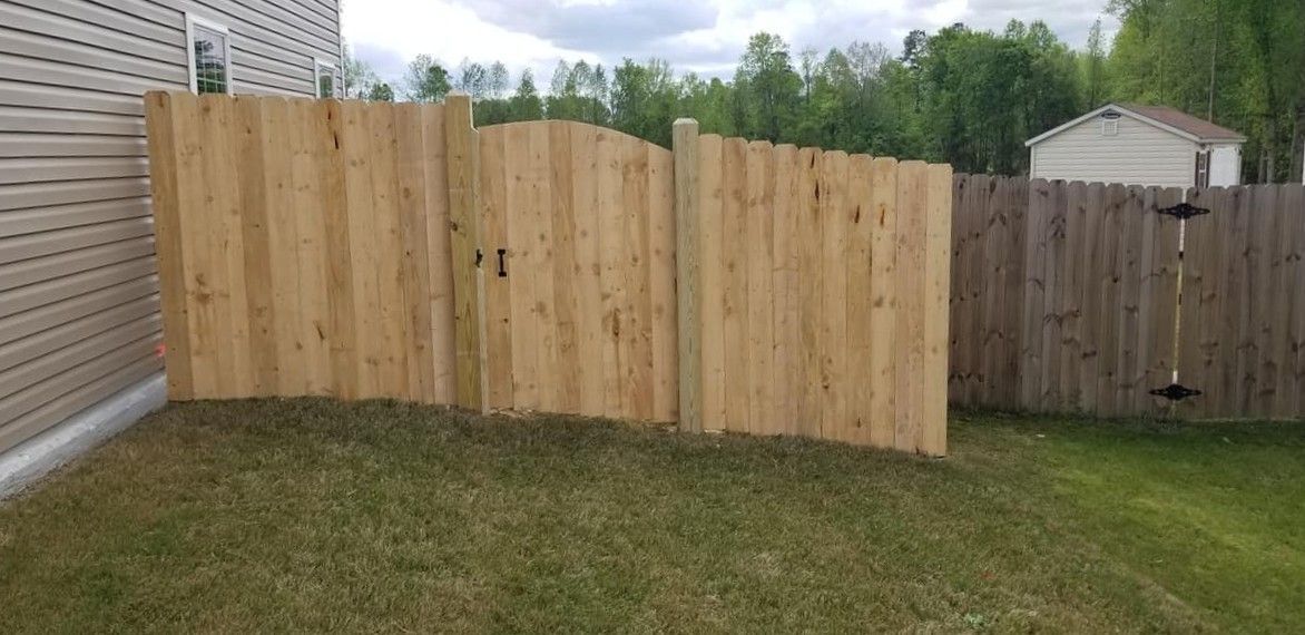 Wooden privacy fence sections in a backyard beside a house and shed
