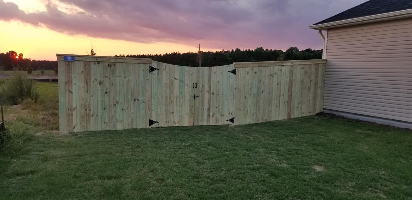 Wooden fence panels blocking a grassy yard beside a house at sunset