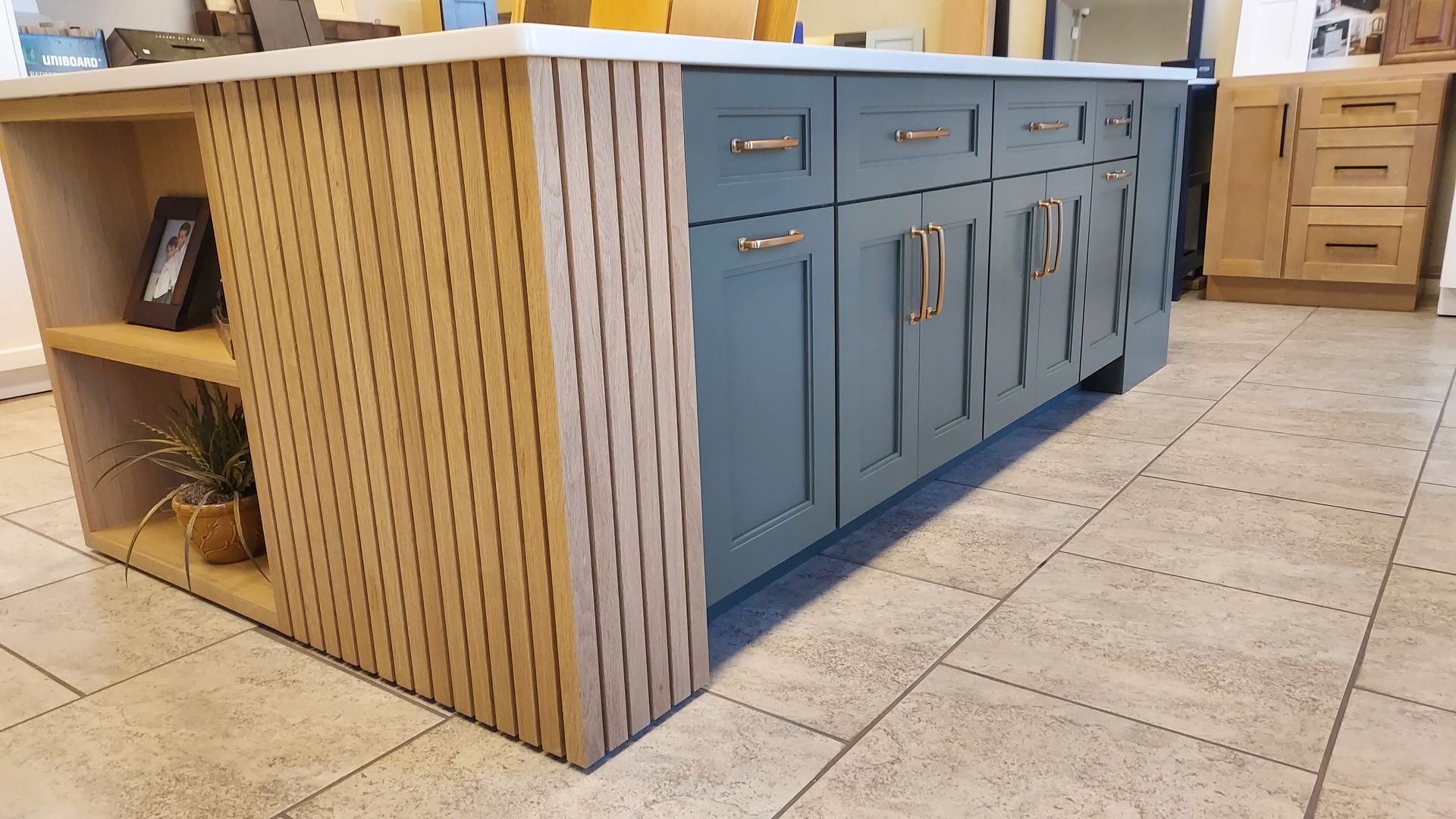 Kitchen island with blue cabinets and a wood slatted side. Beige countertop and tan floor.