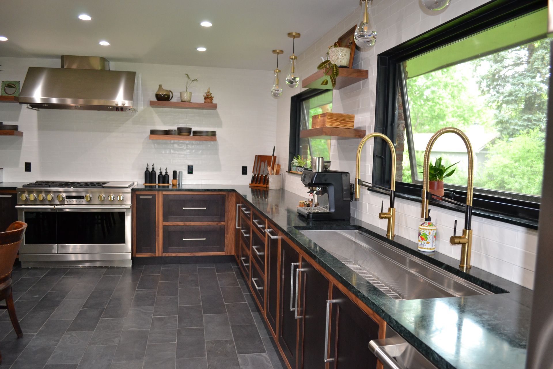 Modern kitchen with dark cabinetry, stainless steel appliances, and gold fixtures.