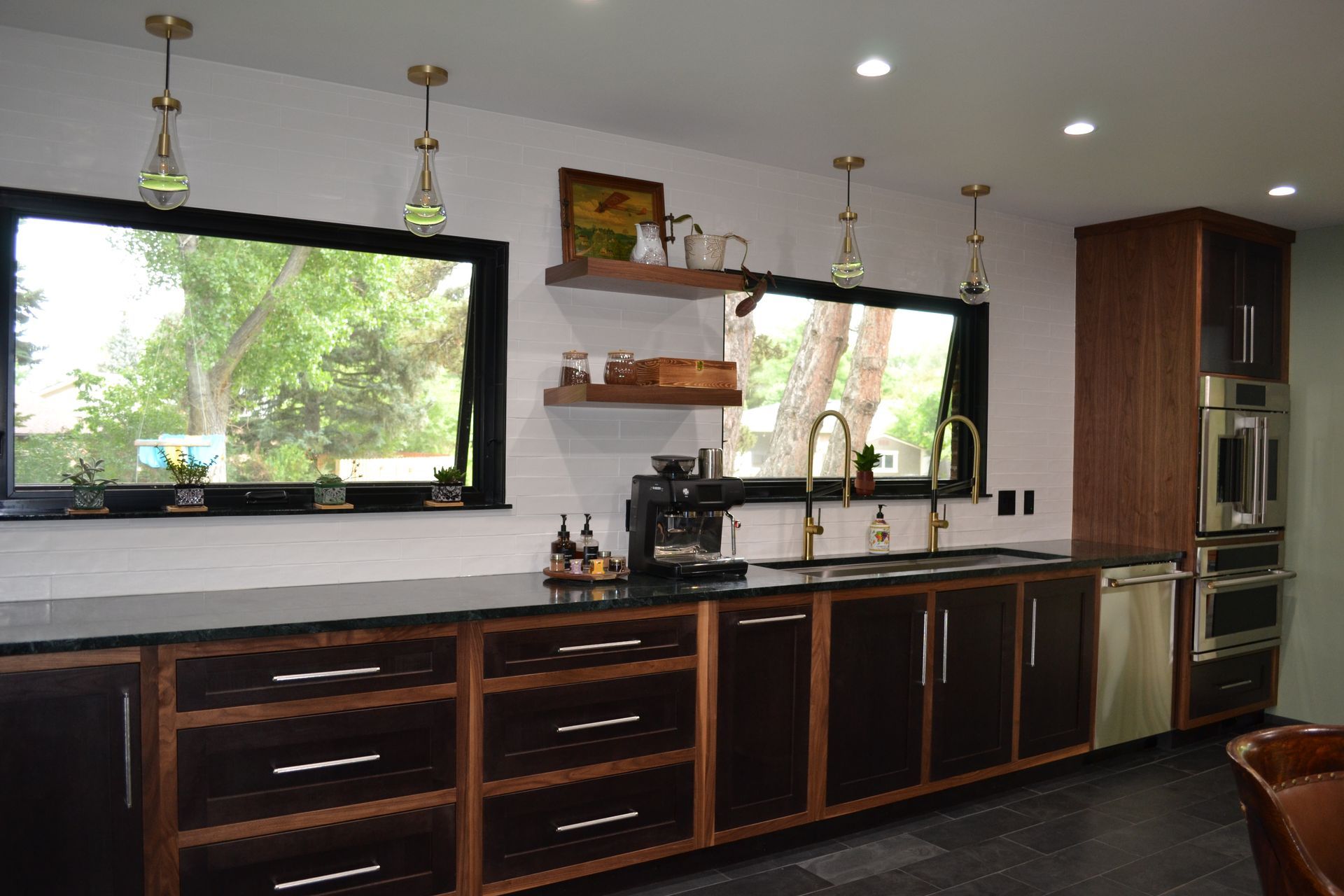 Modern kitchen with dark cabinetry, stainless steel appliances, and gold fixtures.