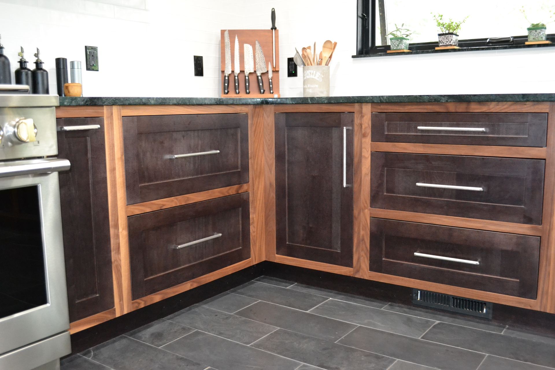 Dark wood kitchen cabinets with stainless steel hardware, granite countertop, and dark tiled floor.