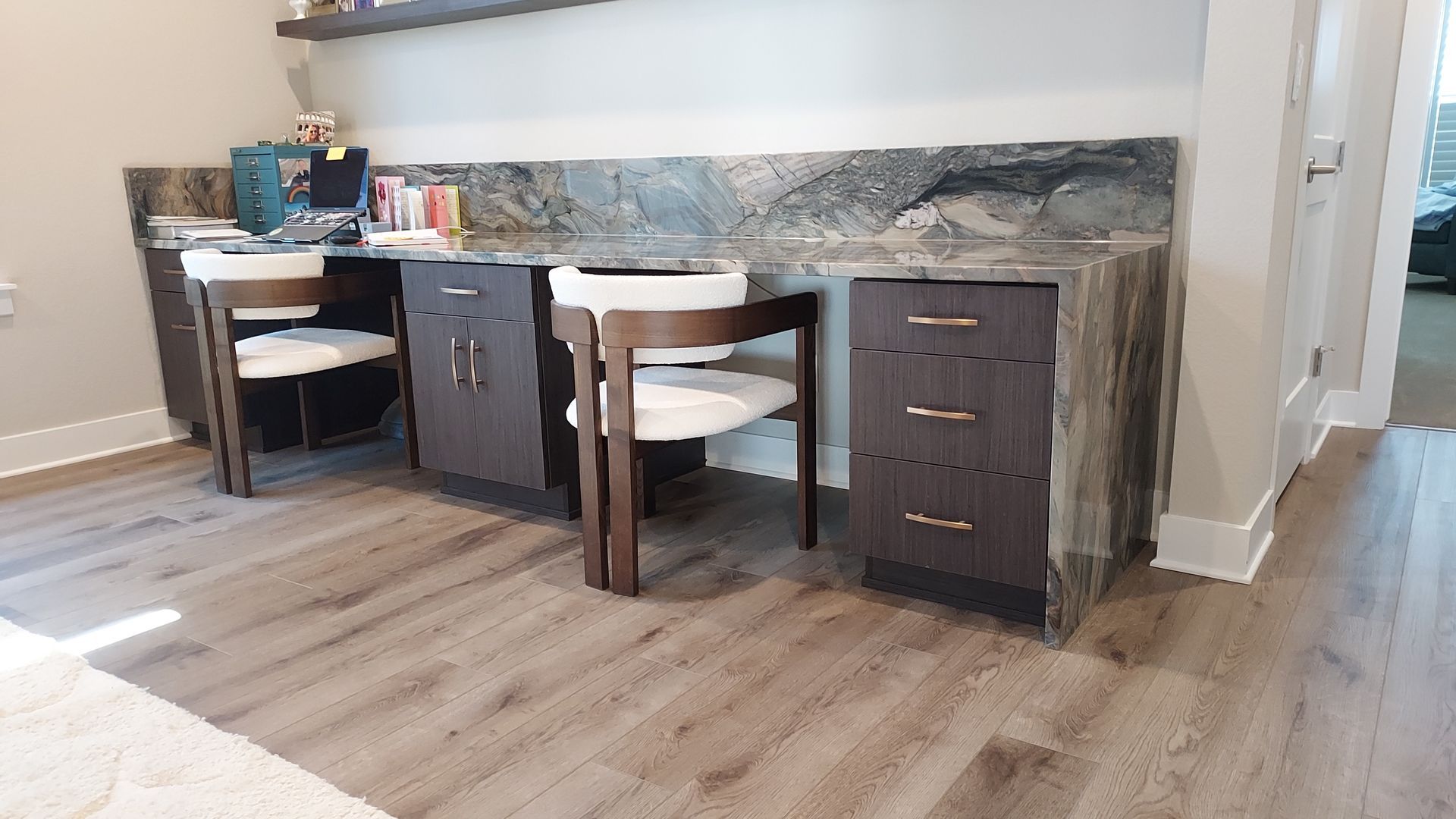 Two dark wood desks with matching chairs and a granite countertop