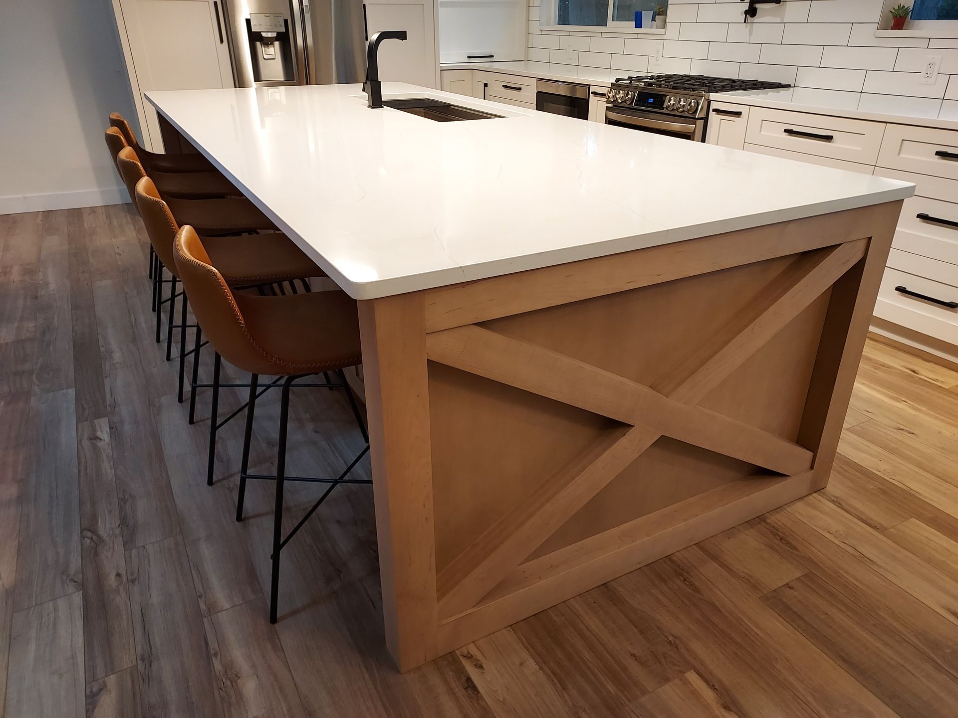 Kitchen island with white countertop, light wood base, and bar stools.