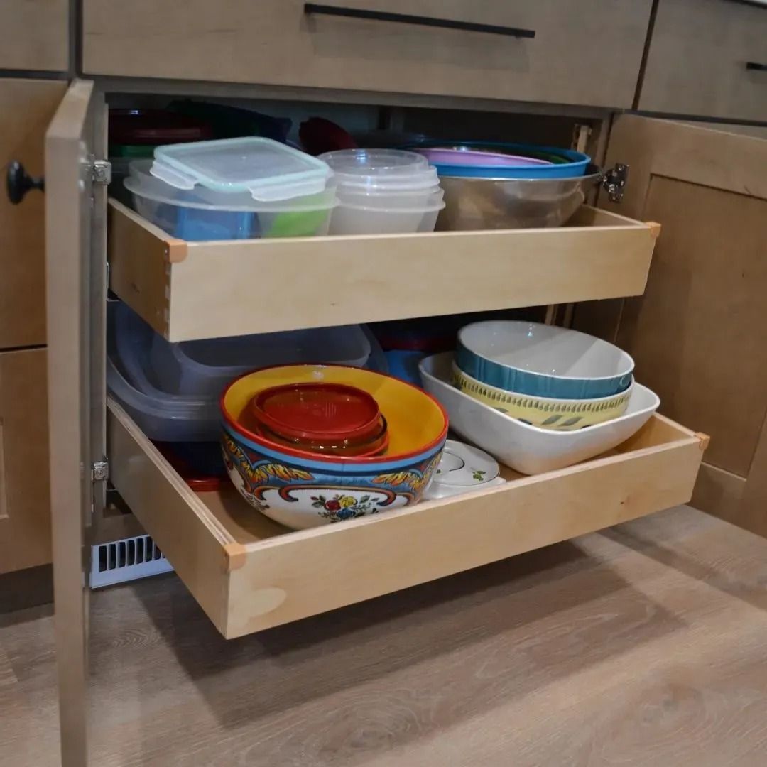 Open kitchen cabinet with pull-out drawers holding bowls and containers.
