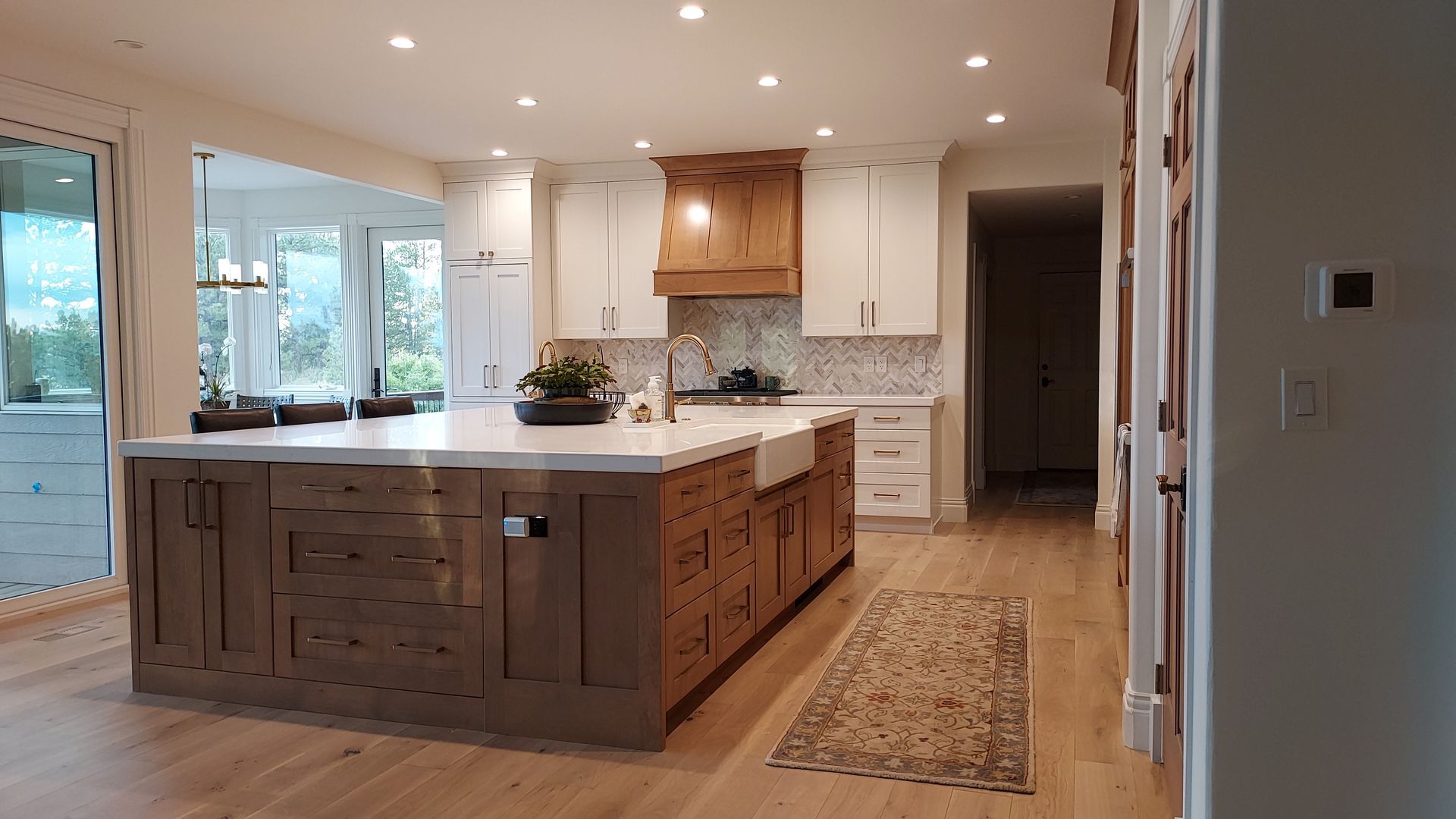 Spacious kitchen with a light wood island, white cabinets, and a wood range hood.