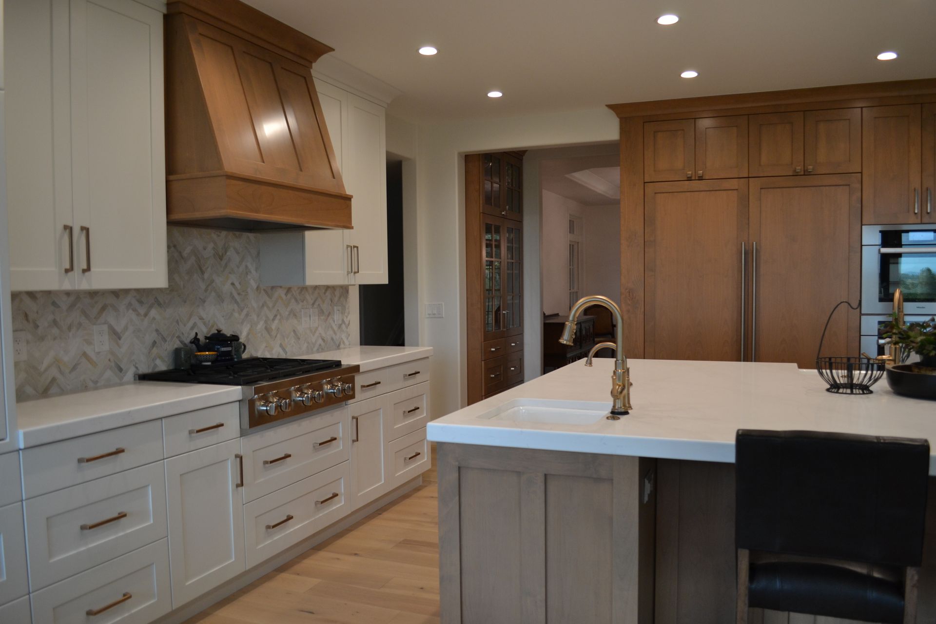 Kitchen with white and wood cabinets, a gas range, and a large island with a sink.