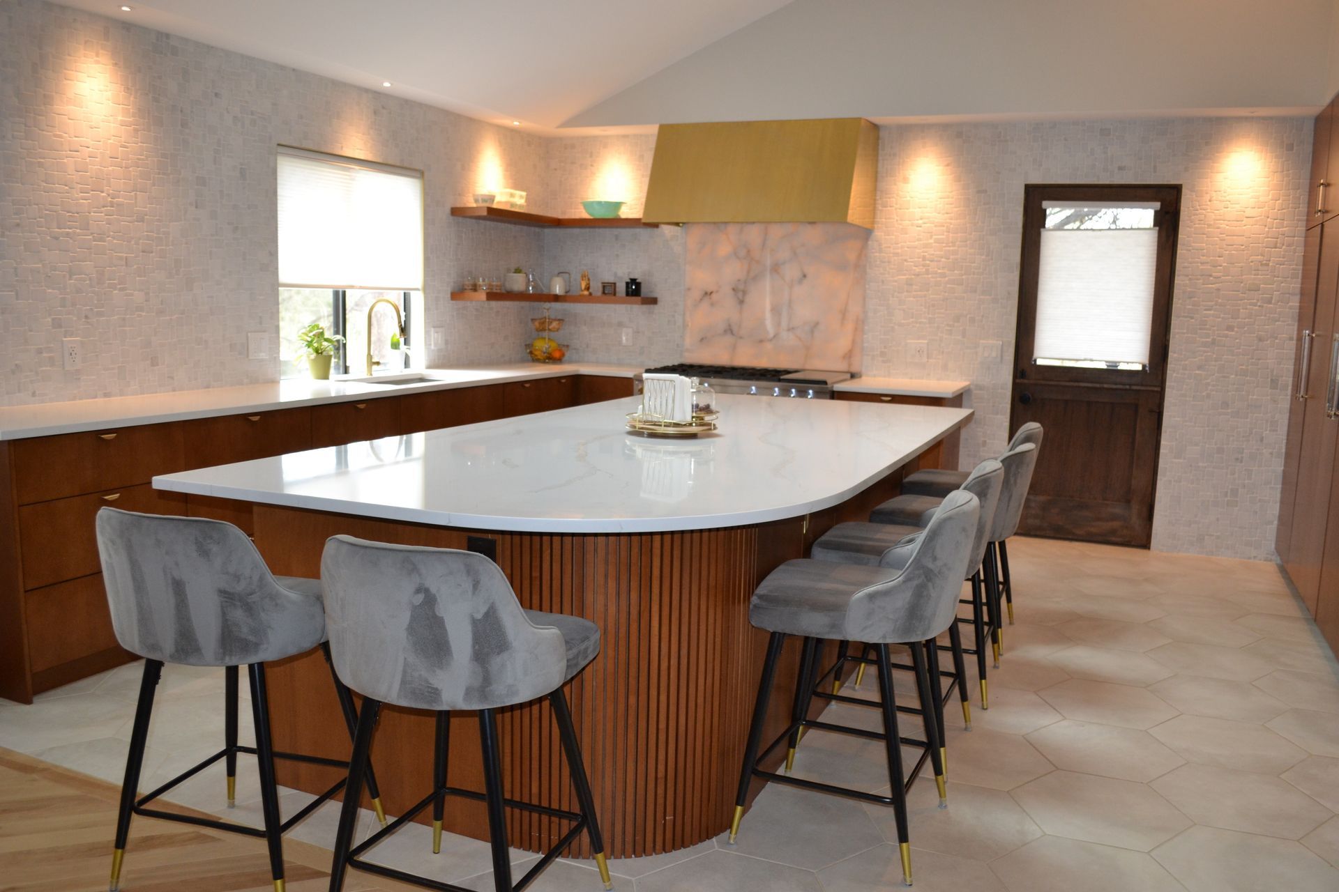 Kitchen with large island, seating, wooden cabinets, and textured backsplash.