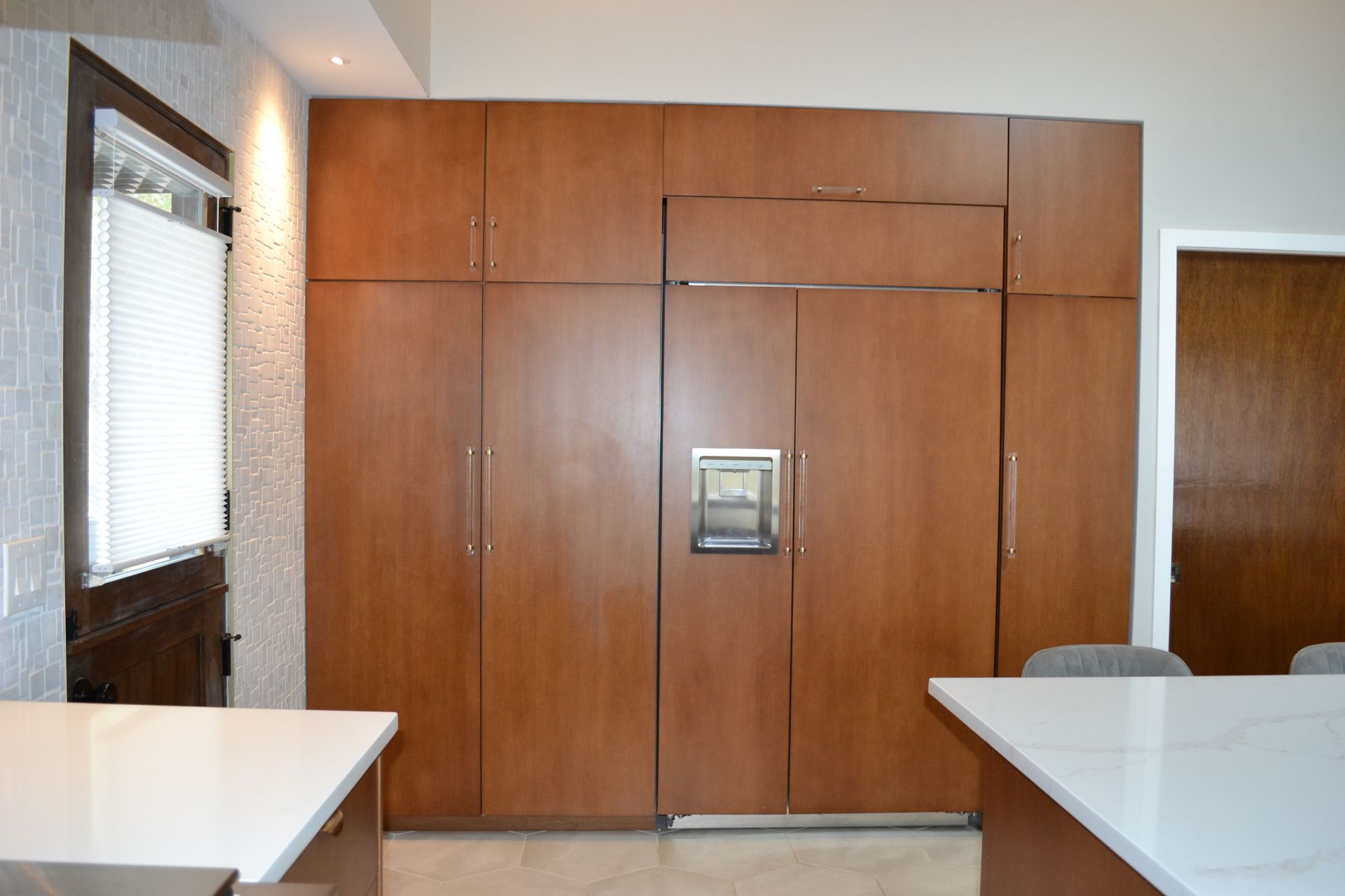 Built-in wooden refrigerator with matching cabinets in a kitchen, next to a door and counter.
