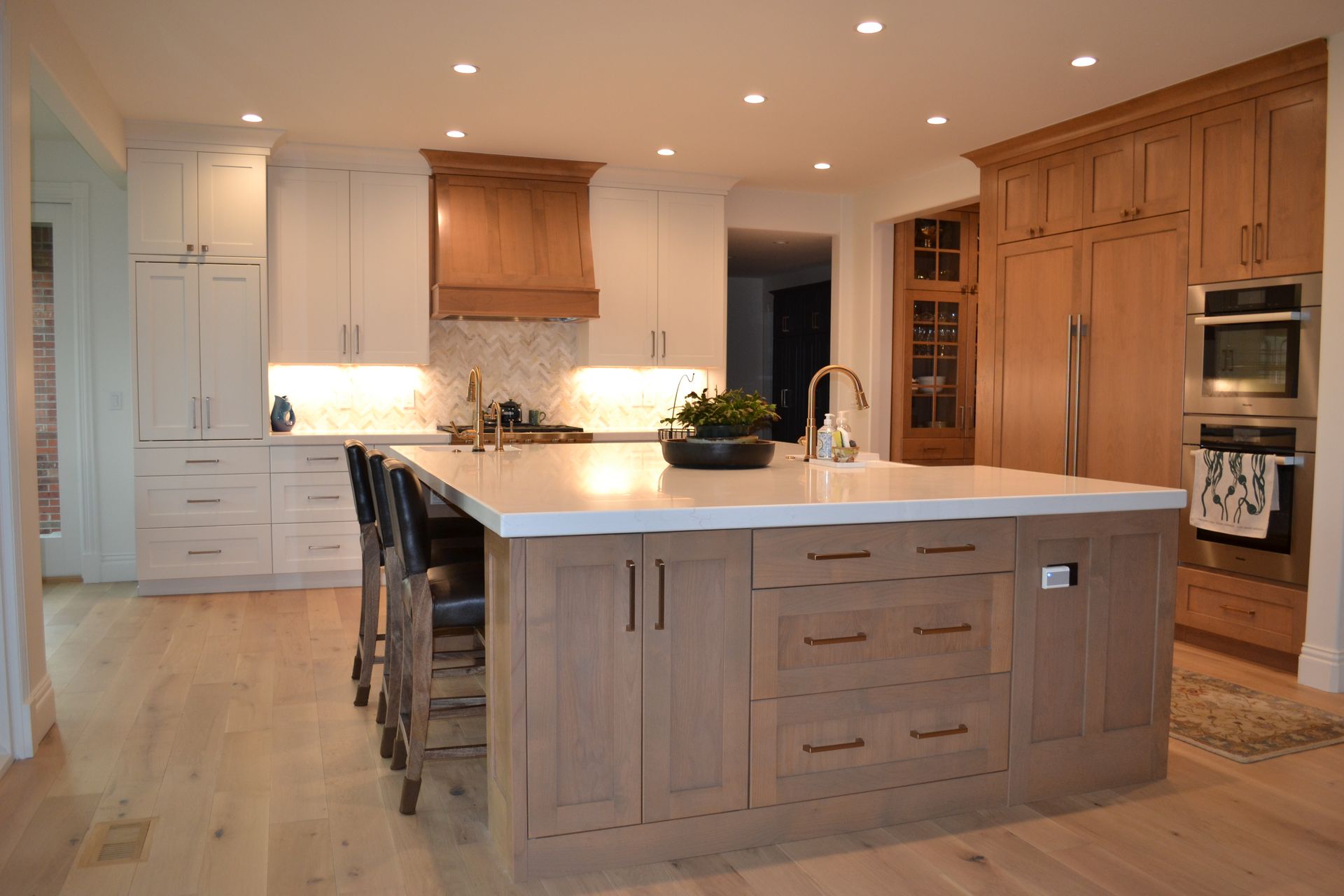 Kitchen with light wood cabinetry and large island, white countertops, and hardwood flooring.