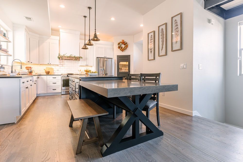 Kitchen with island seating, white cabinets, and three pendant lights.