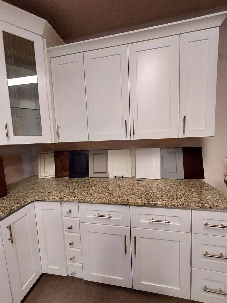 White kitchen cabinets and granite countertop with paint sample swatches.