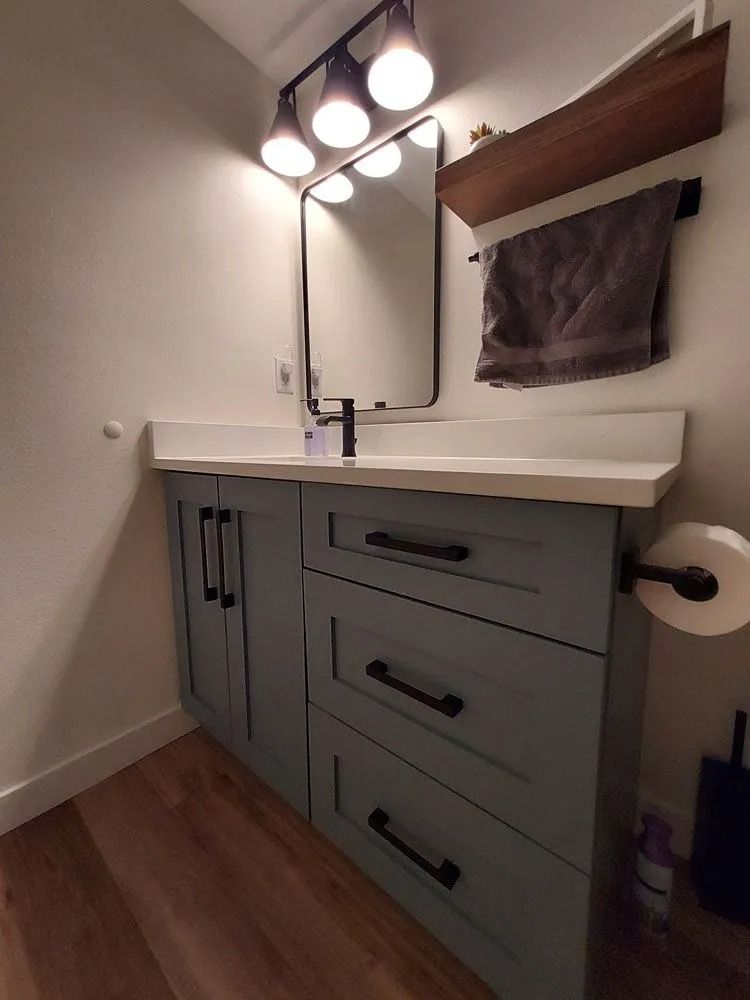 Bathroom with light blue vanity, black fixtures, and a mirror.