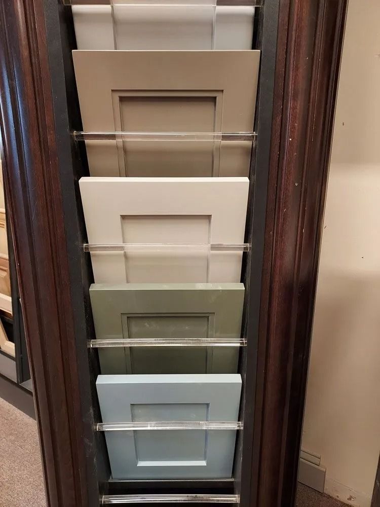 Cabinet door samples in various neutral colors displayed in a wooden rack.