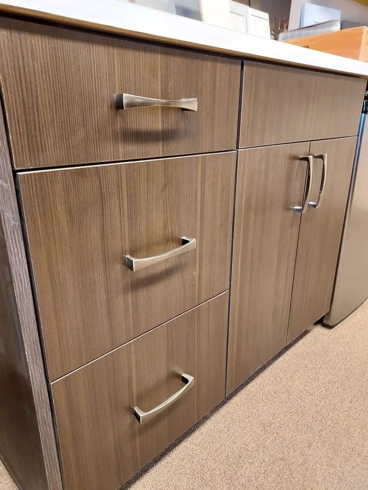 Wooden cabinets with silver handles under a white countertop.