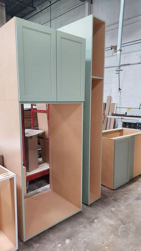 Cabinetry components, including a cabinet box with a door, are arranged in a workshop.
