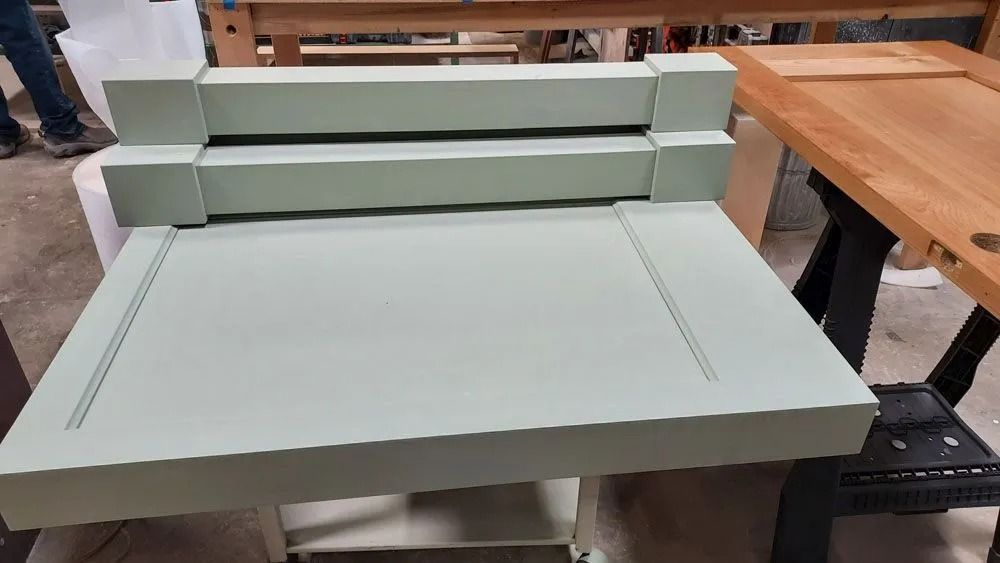 A light-green painted wooden desk with a tiered back in a workshop setting.