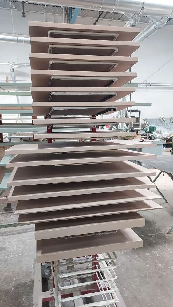 Wooden cabinet doors stacked on a drying rack in a workshop setting.