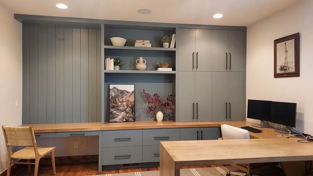 Built-in blue cabinetry with desk area, light wood desktop and a framed landscape photo.