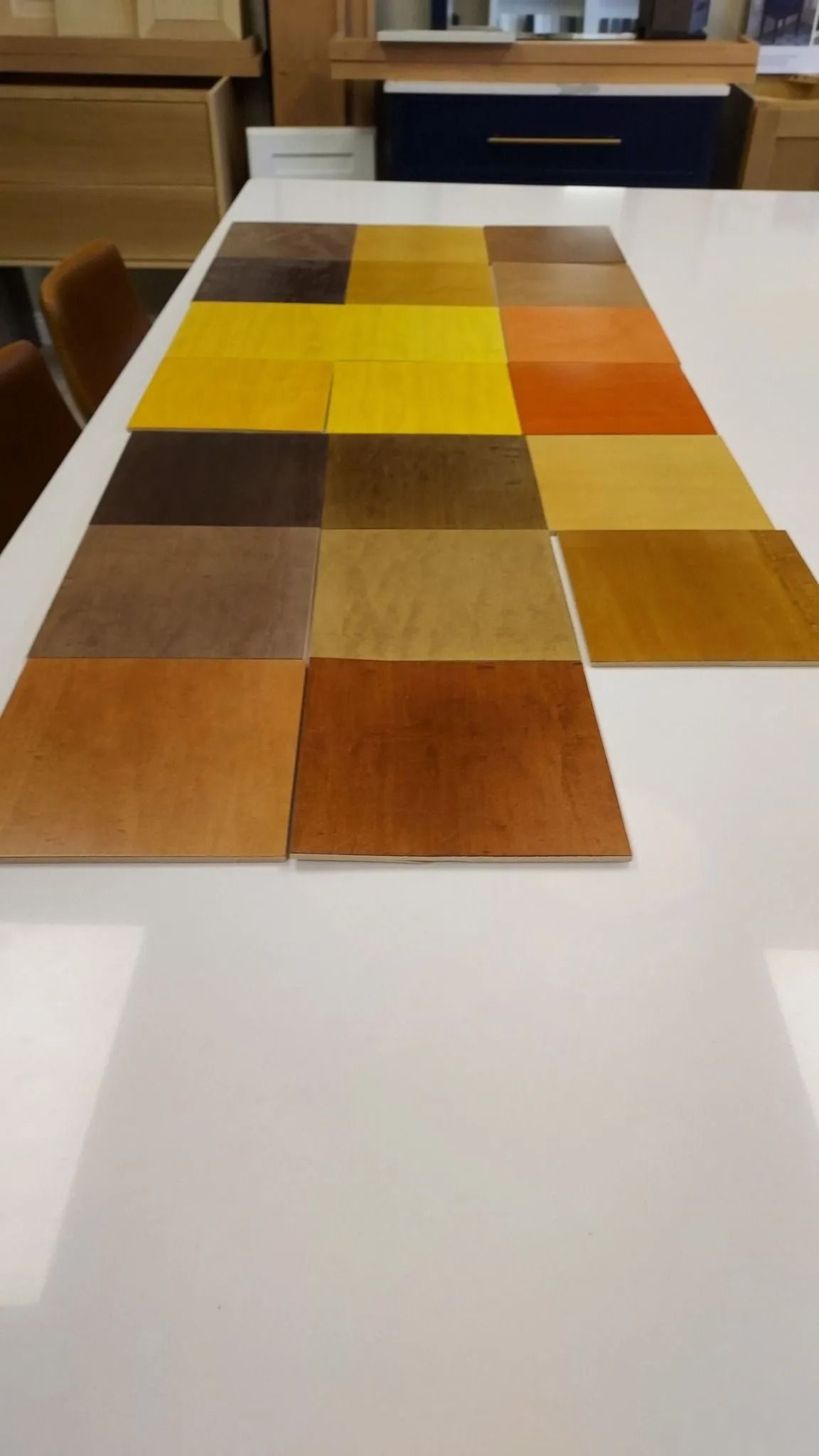 Various wood stain samples in shades of yellow, brown, and orange, displayed on a white surface.