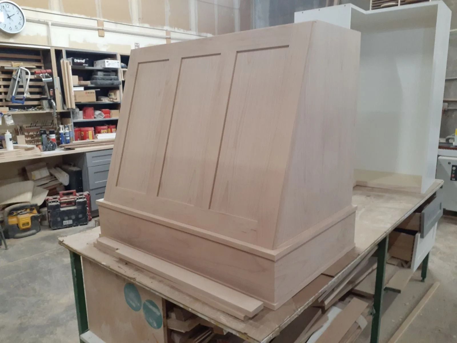 Wooden kitchen range hood under construction on a workbench in a workshop.