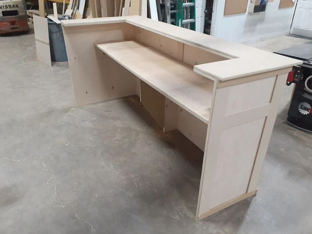 Light wood L-shaped reception desk in a workshop.