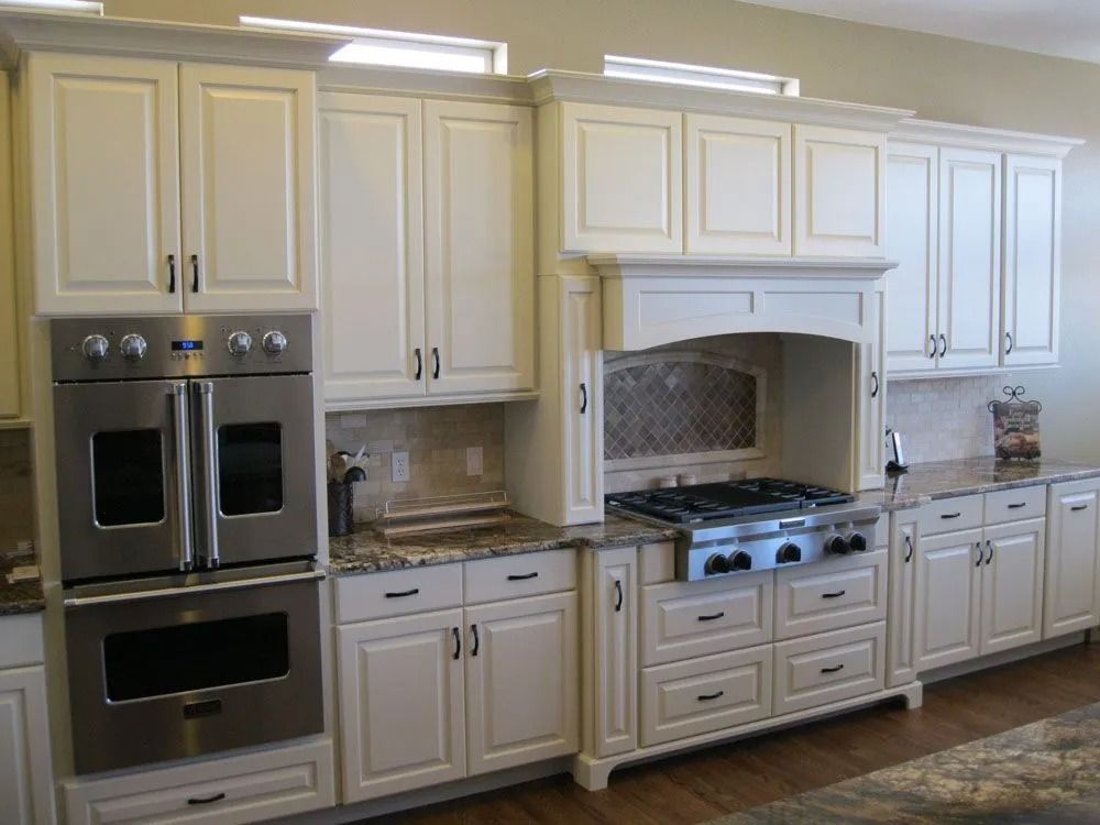 Cream-colored kitchen cabinets with stainless steel appliances, including a double oven and range hood.