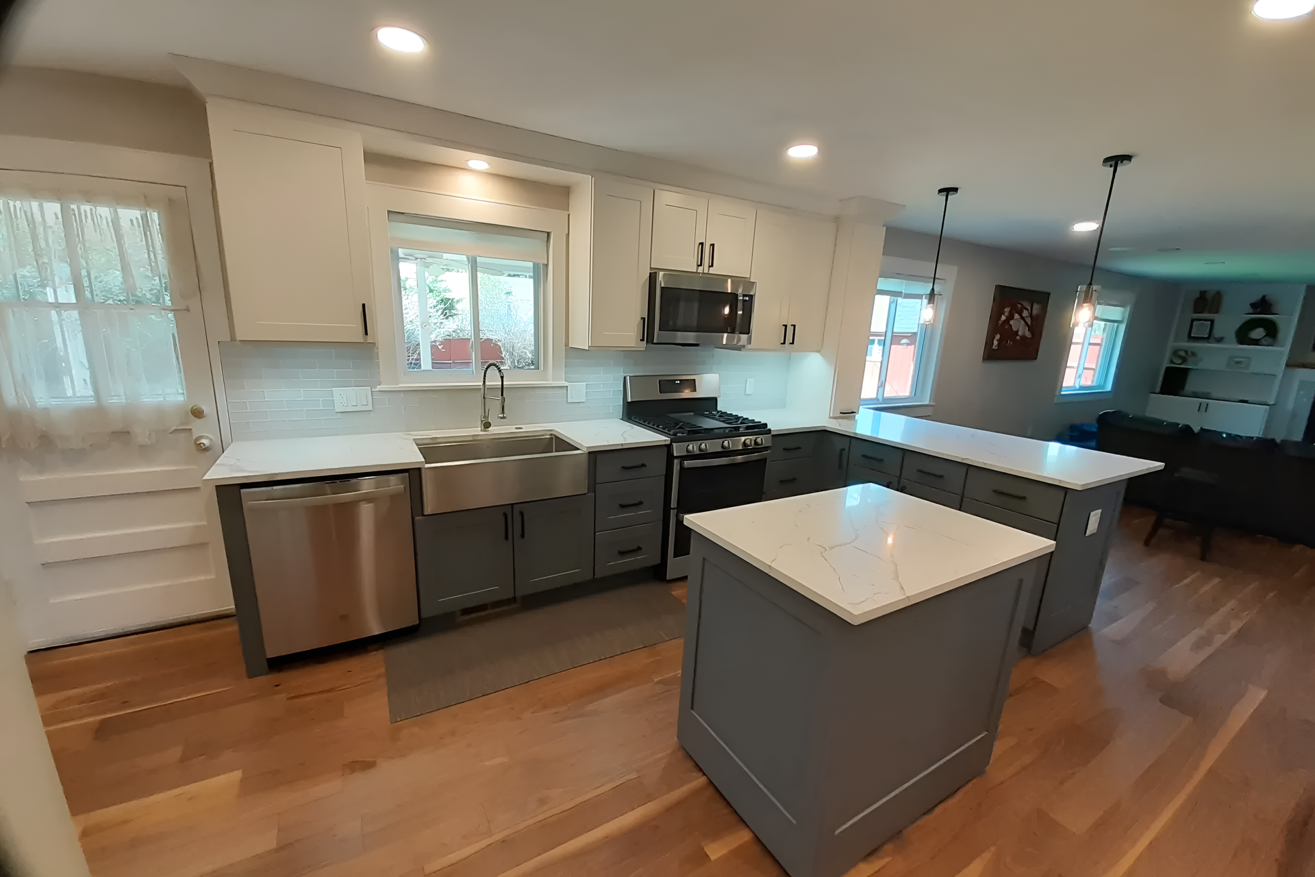 Modern kitchen with white and gray cabinets, stainless steel appliances, and two islands.