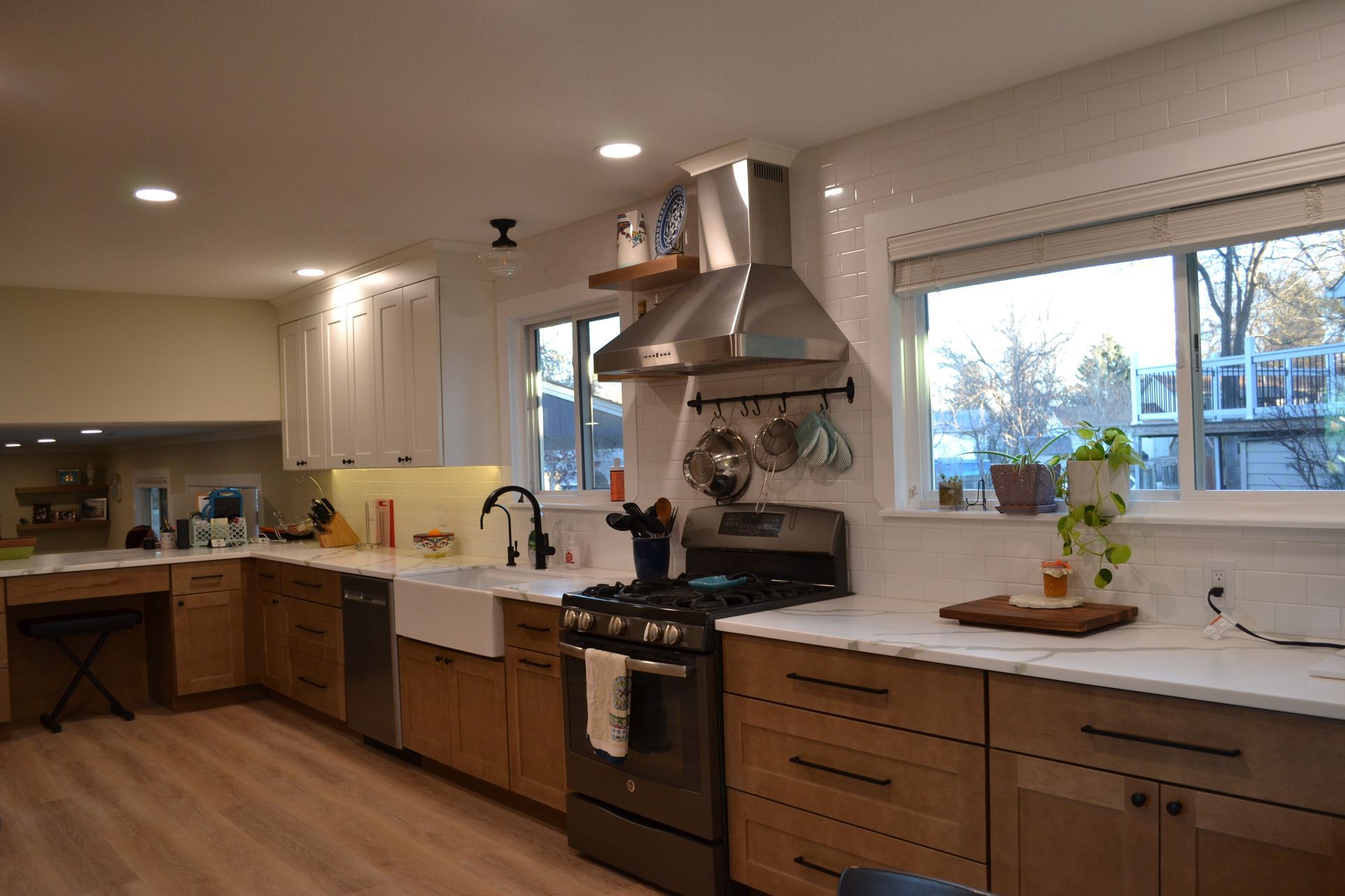 Kitchen with white countertops, wooden cabinets, stainless steel range hood, and large windows.
